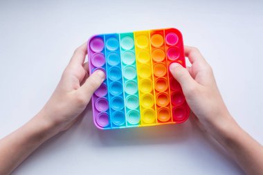 Stres önleyici oyuncağı patlat. Gökkuşağı duyusal kıpırdaması beyaz arka planda elde izole edilmiş. Yeni moda silikon oyuncak.