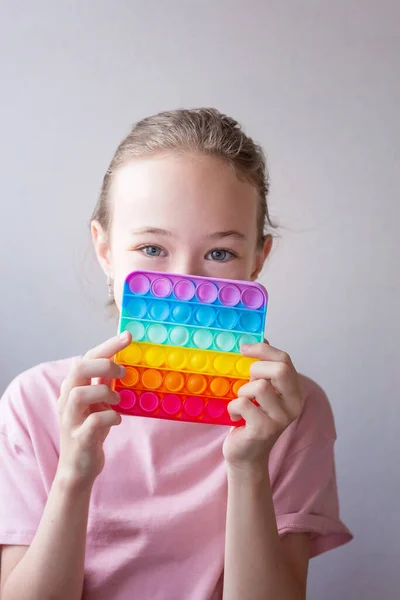 Teenager girl playing with round silicone colorful anti stress pop it toy. Push Pop Bubble in hands. Close up. — Stock Photo, Image