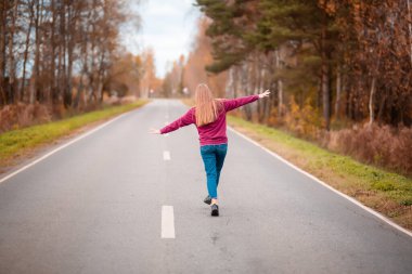 Kırsal kesimde boş yolda yürüyen bir kadın. Macera, spor, egzersiz, özgürlük ve hareket.