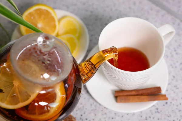 Horký čaj s citrónem a pomerančem, konvicí a bílým šálkem, podávaný s lahodným citrónem a skořicí. Vonící a hřejivý čaj. Krok 2 — Stock fotografie