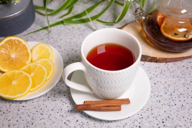 Limon ve portakallı sıcak bir çay, bir çaydanlık ve lezzetli limon ve tarçınlı beyaz bir fincan. Kokulu ve sıcak çay.
