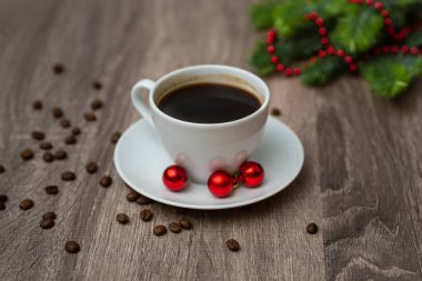 Kahve fincanı ve ahşap masada Noel süslemeleri.