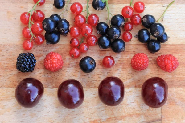 Ягоды красные и черные смородины, малина, ежевика и вишня крупным планом на деревянном столе — стоковое фото