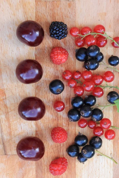 Bær røde og sorte ribs, hindbær, brombær og kirsebær tæt på et træbord - Stock-foto