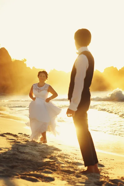 Bruden och brudgummen gå i solnedgången — Stockfoto