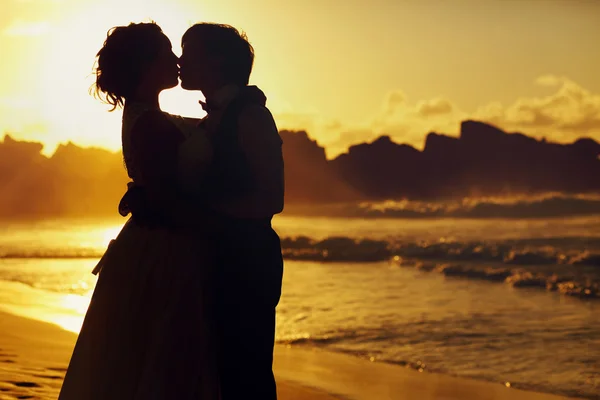 Bruid en bruidegom kussen in de zonsondergang — Stockfoto