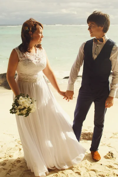 Braut und Bräutigam spazieren am Strand — Stockfoto