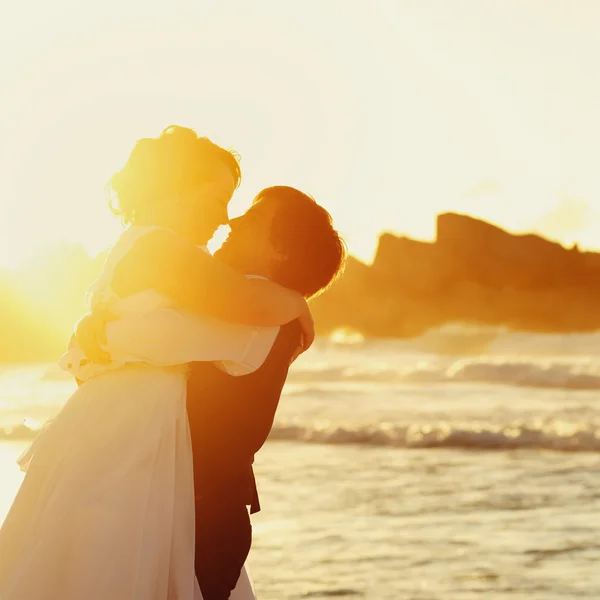 Bride and groom hugging in sunset Stock Picture