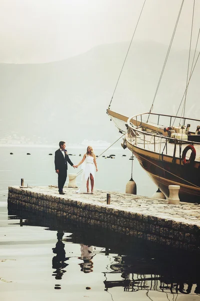 bride and groom walking on the pier near yacht on