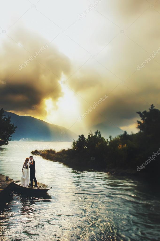 bride and groom stand in boat