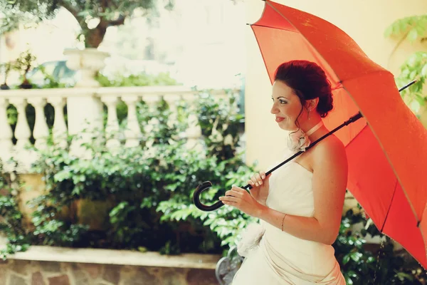 Mosolygó menyasszony alatt piros esernyő — Stock Fotó