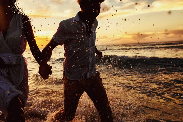 Belo pôr do sol no oceano e casal feliz correndo juntos — Fotografia de Stock