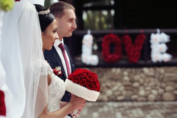 Bruden och brudgummen nära romantiska blomman tecken — Stockfoto