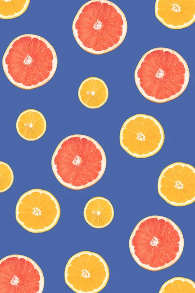 Lemon, orange and grapefruit on a blue background, cut in half and sorted by size. Flat lay