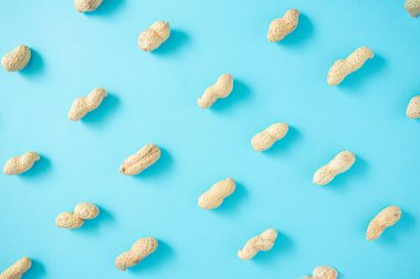 Açık mavi arka planda soyulmamış güzel bir fıstık deseni. Düz konum düzenleme, üst görünüm.