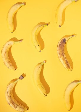 Canlı sarı bir arka planda, yaratıcı, taze, izole edilmiş muz deseni. Düz dizayn