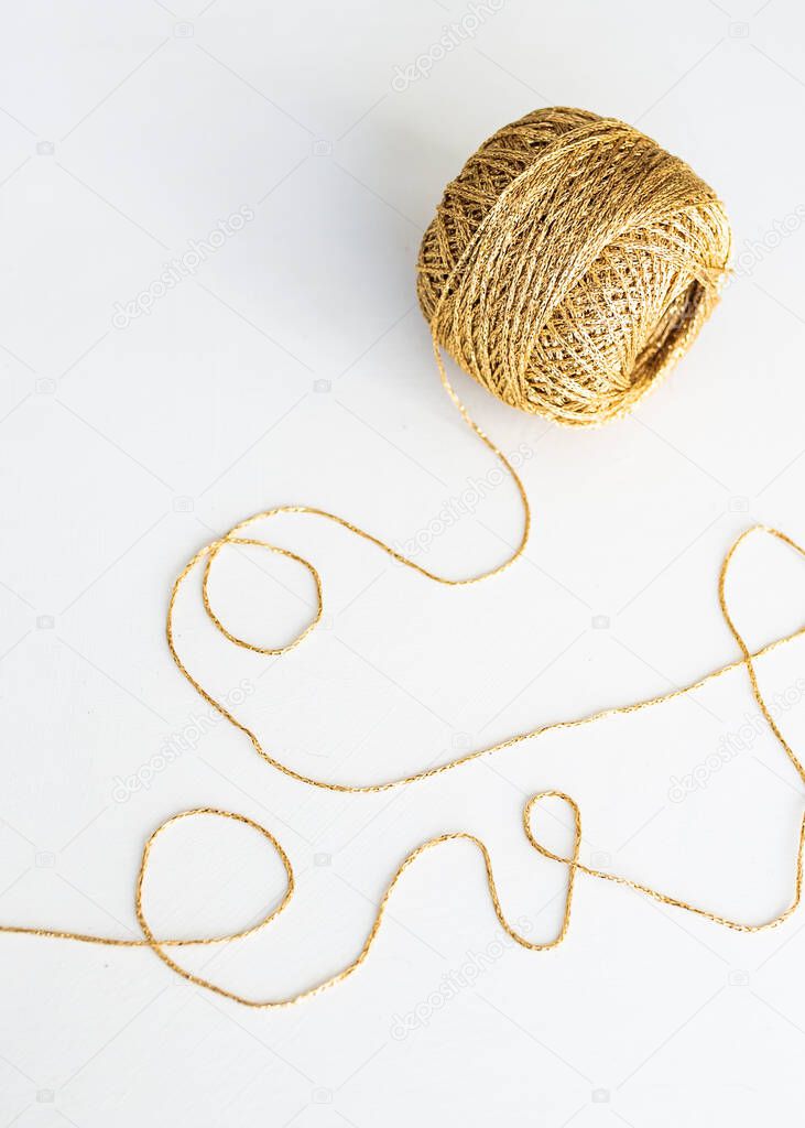 gold skein for knitting on white background