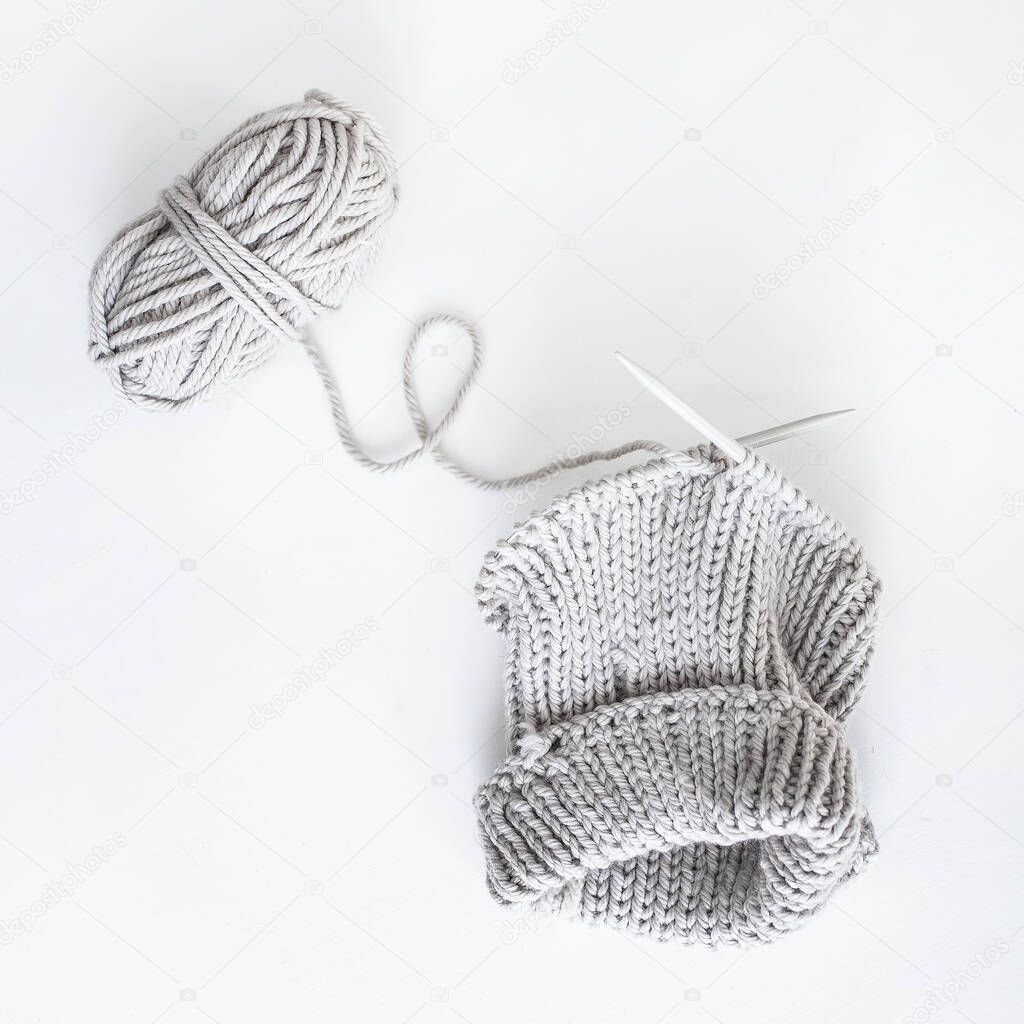 grey knitting yarn and needles on white background