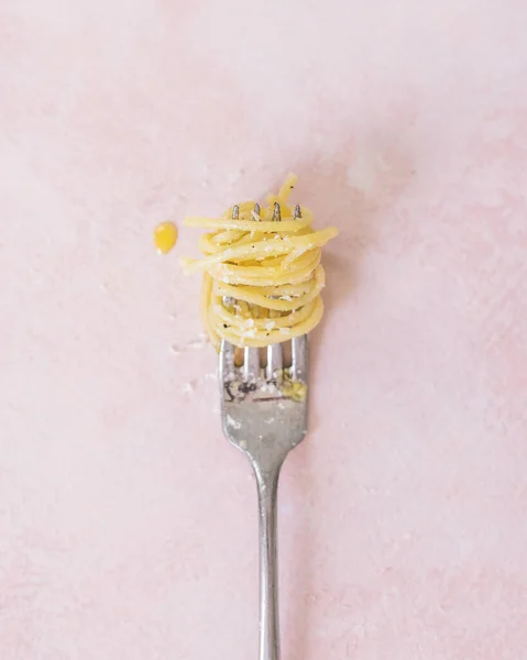 Çatala sarılmış tereyağlı spagetti eriştesi, Pembe desenli arka plan, düz yatış, yakın çekim