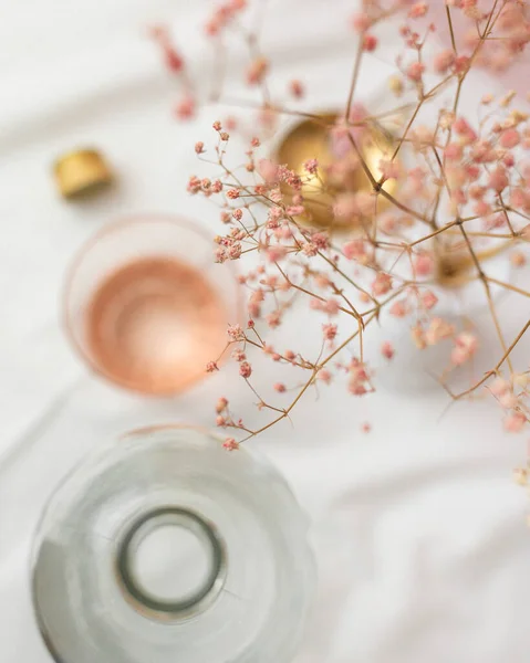 stock image Blush Pink Wine Glass at Place Setting, White Tablecloth, Wine Bottle, Pink Flowers 