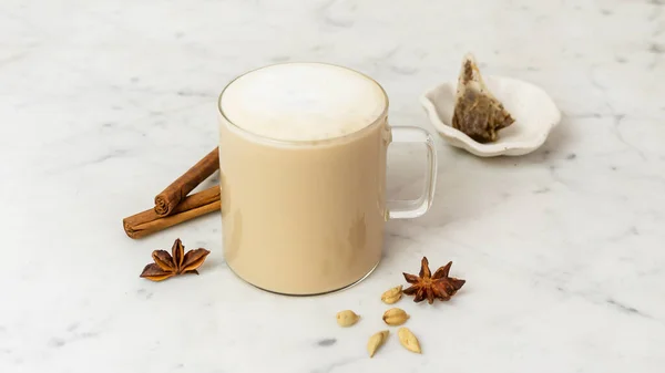 Cam bardakta Chai Tea Latte Baharatlar ve Mermer Arkaplanda Çay Torbası