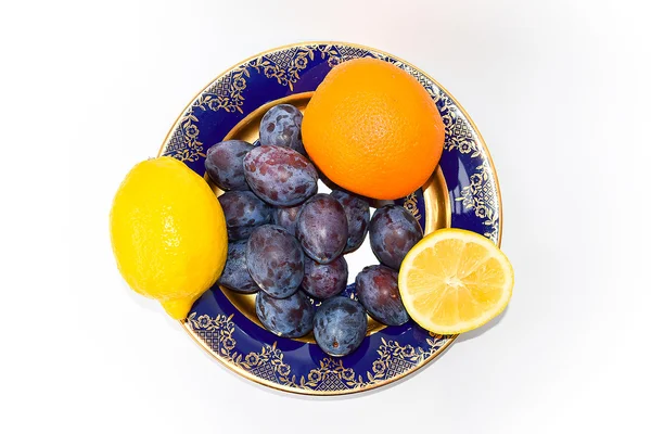 Švestky, citrony a pomeranče na talíři — Stock fotografie