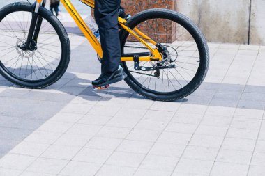 Kaldırımda giderken bisikletle pedal çeviren bir insan.