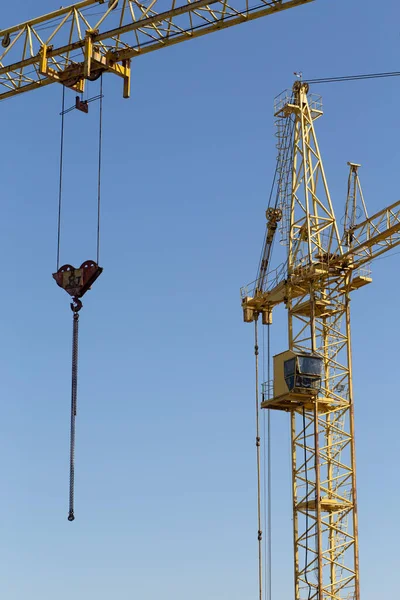 Hydraulic luffing jib tower cranes and workers being poured concrete into foundation. Cement pouring into formwork of building at construction site. Tower cranes constructing a new residential build