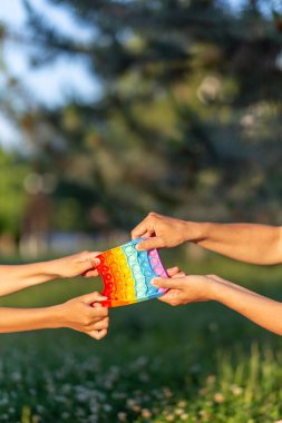 Çocukların elleri, sonsuz pupyrka 'yı doğanın arka planına karşı farklı yönlere çeker. Oyunun adı poppit.