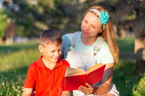 Blondynka Mama Syn Czerwonym Shircie Czytają Książkę Czerwoną Okładką Naturze — Zdjęcie stockowe