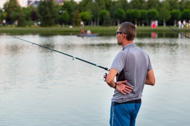 Bir adam bir balık yakalar, gölde balık tutarken olta çeker ya da gölette yazı yazmak için boşluk bırakır.