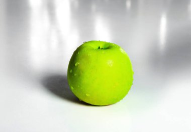 İzole edilmiş yeşil elma ve beyaz masaya çiy damlası