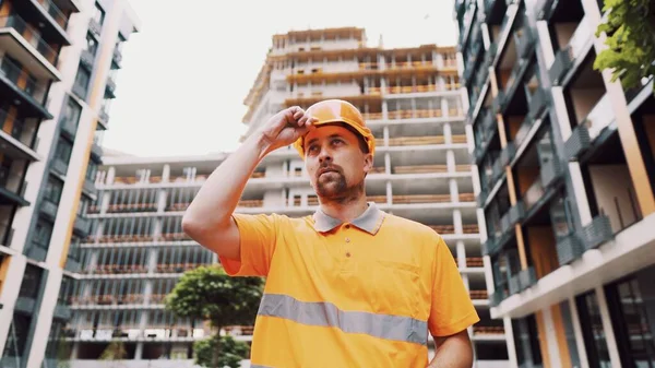 建設労働者は職場で彼の安全装置ヘルメットを置く 安全第一職業概念 ビルダーはハード帽子の制服を着用し 仕事の準備をします 男はキャップオレンジ建設現場に置きます — ストック写真