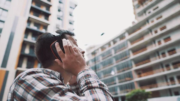 Builder covers his ears, ear muff to protect workers ears. Construction worker wearing protective ear defenders. Concept of construction, taking care of safety during work. Protection against injury.