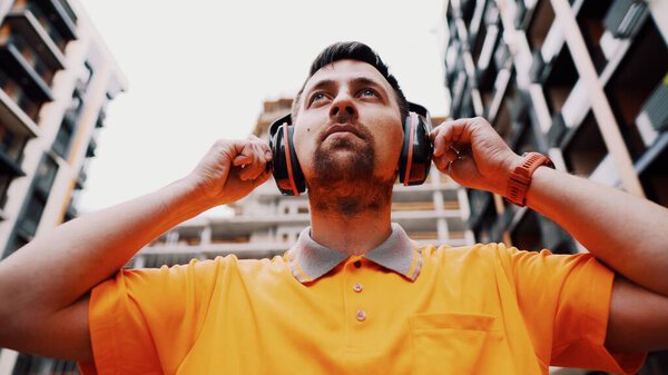 Man wearing safety equipment hearing protection. Worker wearing noise cancelling ear defenders or ear muffs. Construction builder puts on protect ears with headphones. Taking care safety during work.