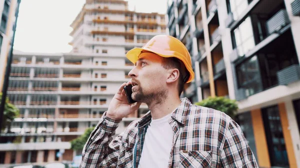 エンジニアが電話で話してる 建築現場で電話を使って建築家 フォアマンの電話制御プロセス 建設業界における建設労働者のコミュニケーション 専門電話の構築 — ストック写真