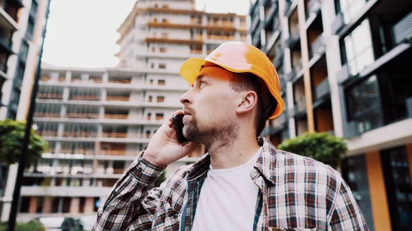 Engineer talking on phone. Architect using phone on construction site. Foreman phone call control process. Construction worker communications in construction industry. Building professional phone.
