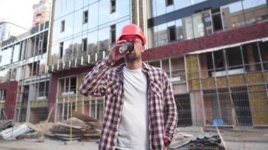 Apartman yöneticisi kahve içiyor. Kahve molasında mimar. İnşaat işçisi kahve fincanıyla ayakta duruyor. Koruyucu giysili, turuncu kasklı bir adam rahatlamak için kahve içer.