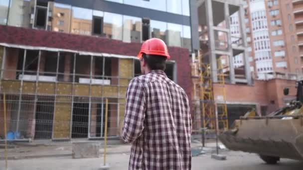 Supervisor do edifício a beber café no local. Arquiteto na pausa para o café. Trabalhador da indústria da construção em pé com caneca de café. Homem de equipamento de proteção capacete laranja bebe café para ir e relaxar — Vídeo de Stock