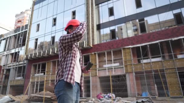 Costruttore ingegnere che fa una pausa caffe 'in cantiere. Uomo caucasico con tazzina da asporto e attrezzatura protettiva si è rotto mentre si lavora in loco. Operaio edile bere caffè — Video Stock