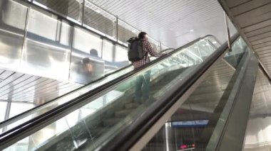 Boş tren istasyonu binası, karantina sırasında koruyucu maske takan yürüyen merdivendeki tek yolcu. Uçuşların iptal edilmesi ve ulaşım çöküşü. Yürüyen merdivendeki yolcu.