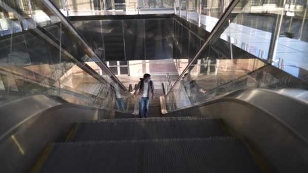 Hombre caucásico con máscara protectora sube escaleras mecánicas en la terminal vacía del aeropuerto. Viaje durante el virus epidémico de la corona covid 19. Mantenga una distancia segura. Masculino en máscara va a puerta para viajar en avión — Vídeo de stock