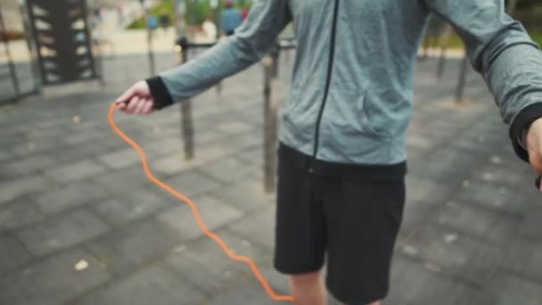 Un atleta aprende a saltar la cuerda en un campo de deportes al aire libre de la ciudad. Ejercicio cardio de quema rápida de calorías. Hombre en el gimnasio urbano fuera de entrenamiento y fitness saltar la cuerda. Concepto de deporte, entrenamiento y estilo de vida — Vídeo de stock