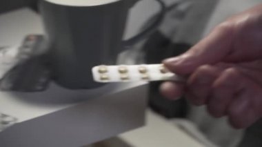 Ev tedavisi. Genç beyaz erkek, akşamları yatakta otururken yatak odasında ilaç alıyor. Grip ve bulaşıcı hastalık mevsimi. Covid 19 koronavirüs salgını sırasında tedavi