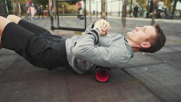 En idrottare som tränar på en skumrulle för högdensitetsmassage mot ryggsmärta. Rulla för sjukgymnastik trigger punkt och motion. Djup vävnadsmassage, smärta, yoga, benmuskler — Stockvideo