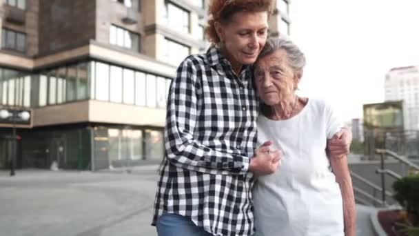 Concepto de valores familiares. Señora mayor con su madre anciana con demencia, abrazando y sonriendo caminando por la ciudad. Feliz anciana con hija. Envejecido, mental. Roles cambio de cuidado a medida que envejece — Vídeo de stock