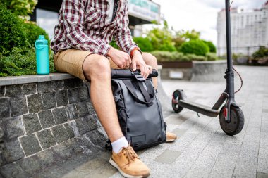 Çevre dostu elektrikli taşıma aracıyla denek teslimatı. Teslimatçı geldi ve malları müşteriye götürmek için sırt çantasını açtı. Ofisin yanındaki sırt çantalarını açan kişi.