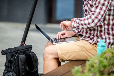 Adam dokunmatik dokunmatik ve dizüstü bilgisayarın tuş takımını kullanıyor, yakın plan eller. Klavyede erkek eller, iş adamı konsepti, açık havada çalışma, online iletişim. Serbest Çalışan Dışarıda Çalışıyor.