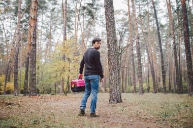 Yasadışı hayvan gömme teması. Ormanda self-servis hayvan mezarı. İnsan, yanında ölü kedi ya da köpek ve ormana gömmek için büyük bir kürek taşıyan taşıyıcı taşır. RIP evcil hayvan.