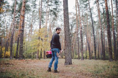 Tema evcil hayvanın ölümü. Bir elinde mezar kazmak için bir elinde kürekle orman yolunda yürüyen bir adam ve içinde bir hayvan olan diğer nakliye kutusunda. Kedinin son yolu.